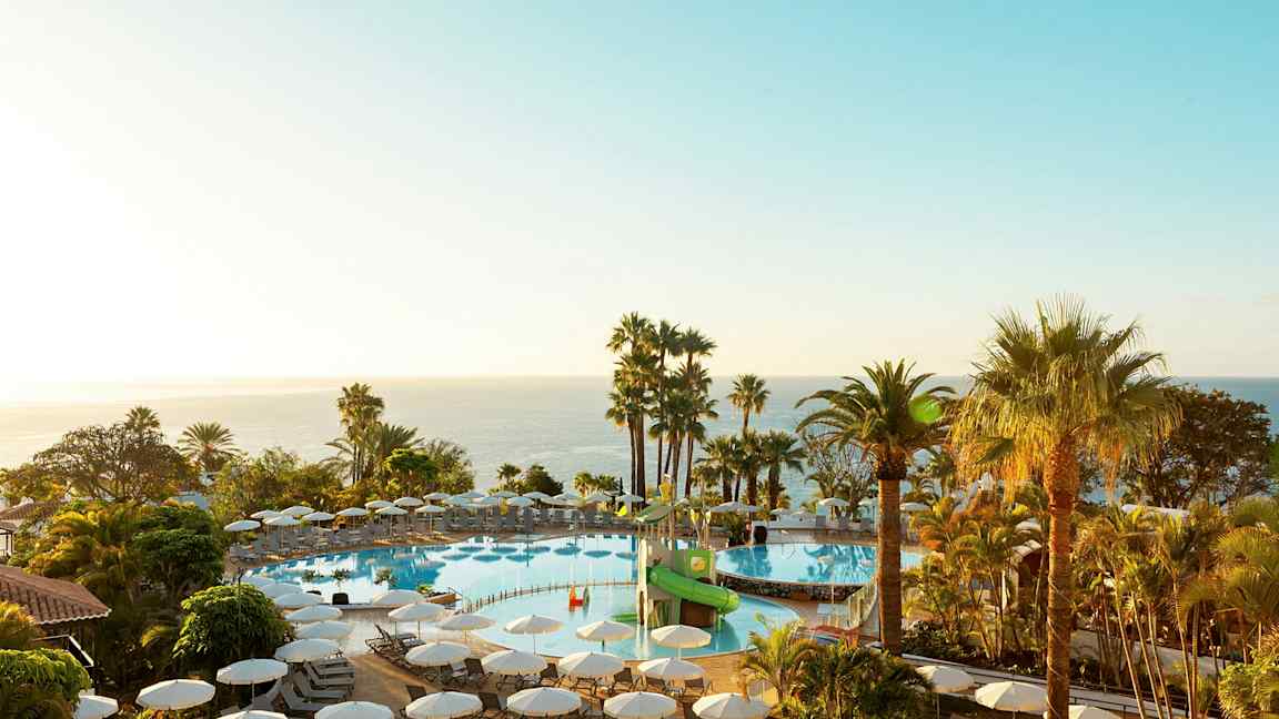 Ulkouima-allas, jonka ympärillä aurinkotuoleja ja palmuja, näkymä merelle. (Tekoälyn luoma teksti)