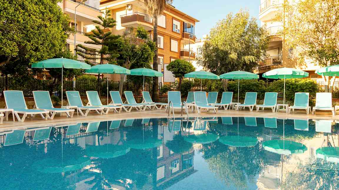 Ulkouima-allas, jonka ympärillä on aurinkotuoleja ja varjoja, taustalla rakennuksia. (Tekoälyn luoma teksti)