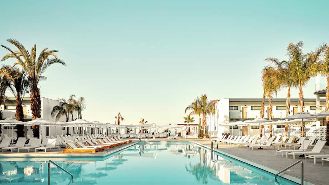 Uima-allas, jonka ympärillä on aurinkotuoleja ja palmuja hotellin yhteydessä. (Tekoälyn luoma teksti)