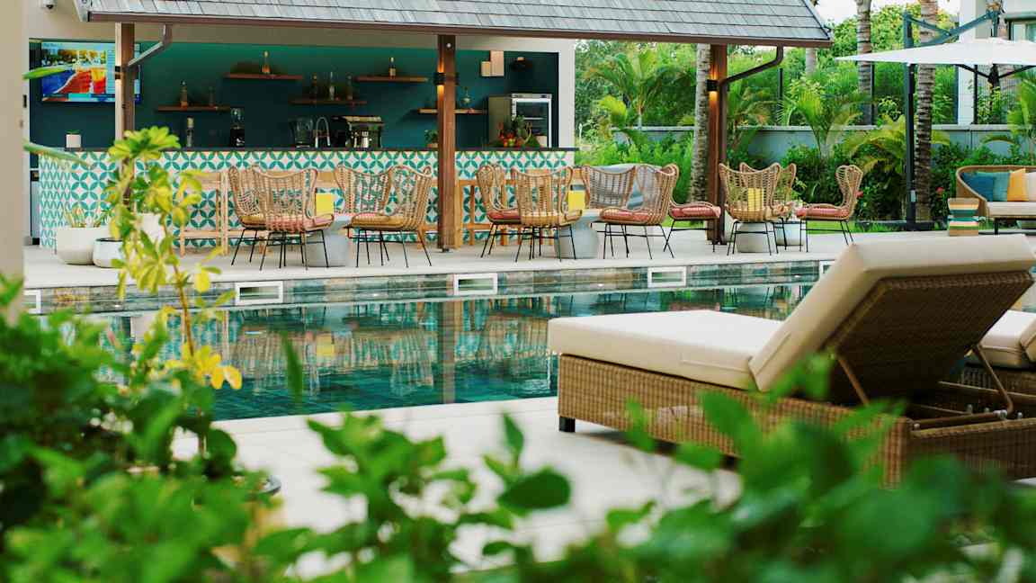 Kuva uima-allasalueesta, jossa on aurinkotuoleja ja baari taustalla. (Tekoälyn luoma teksti)