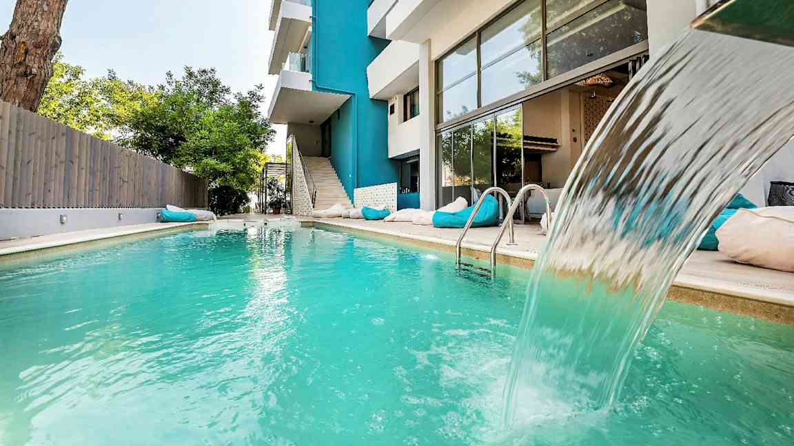 Ulkouima-allas vesiputouksella modernin rakennuksen vieressä. (Tekoälyn luoma teksti)