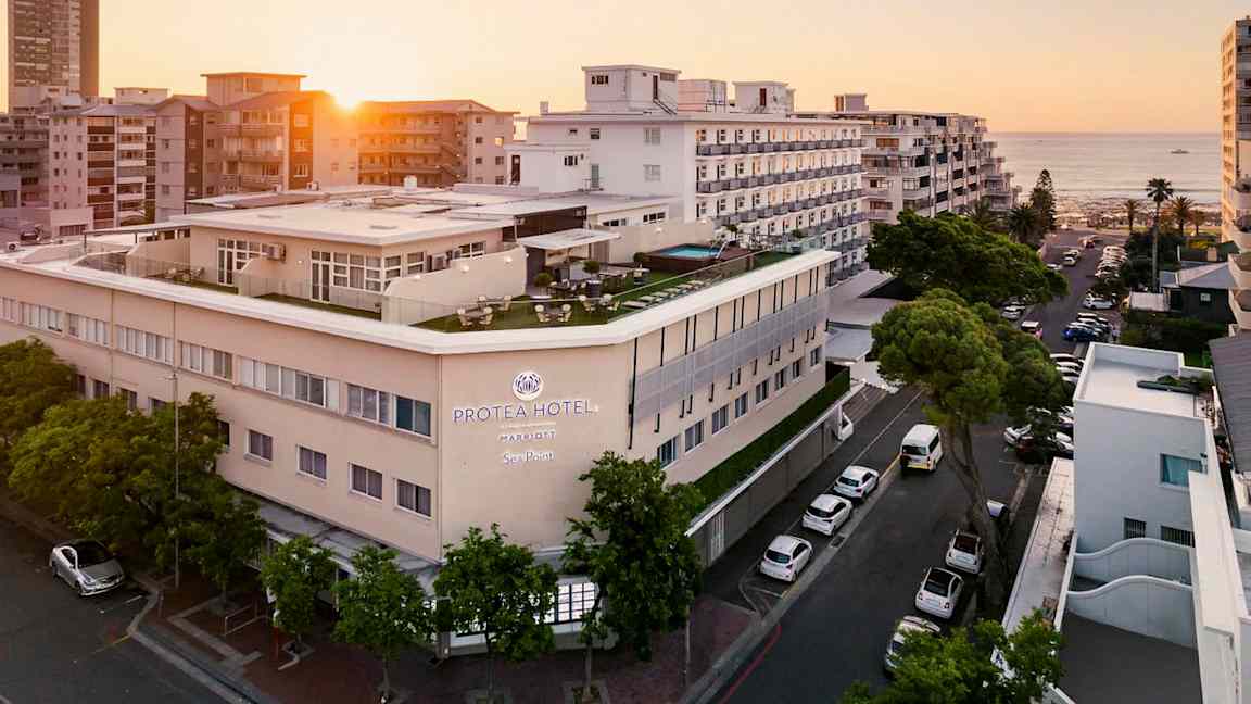 Hotellirakennus meren rannalla muiden rakennusten ympäröimänä auringonlaskussa. (Tekoälyn luoma teksti)