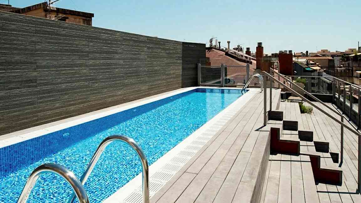 Kattoterassi, jossa on pitkä uima-allas, jota ympäröi terassilattia ja vieressä istuimia. (Tekoälyn luoma teksti)