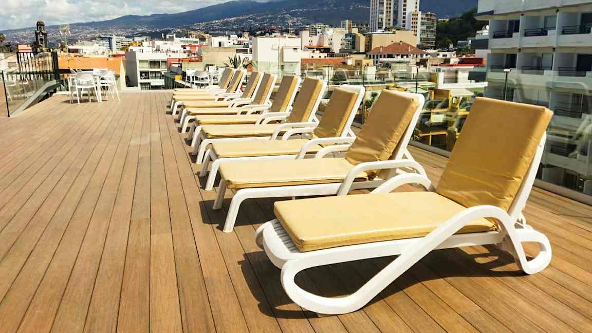 Kattoterassi, jossa on aurinkotuoleja ja näkymä kaupunkiin sekä ympäröiviin vuoriin. (Tekoälyn luoma teksti)