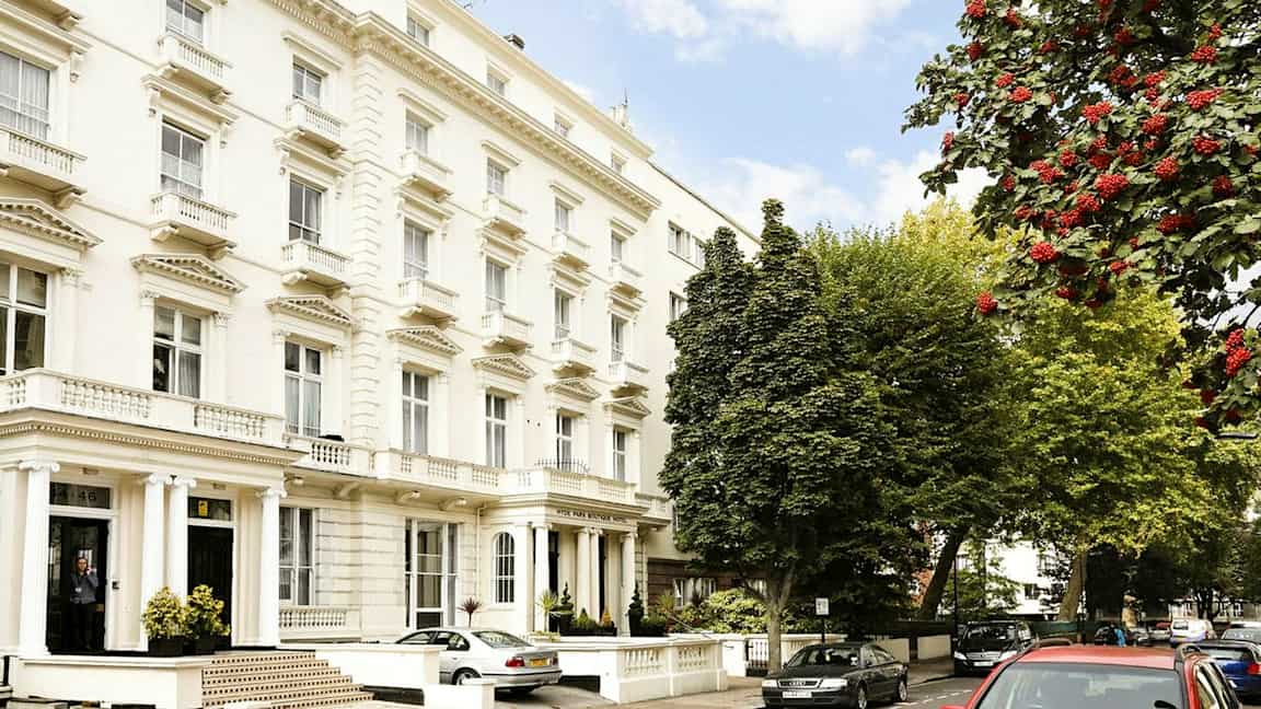 Useita valkoisia rakennuksia klassisella arkkitehtuurilla kadun varrella, ympäröitynä puilla. (Tekoälyn luoma teksti)