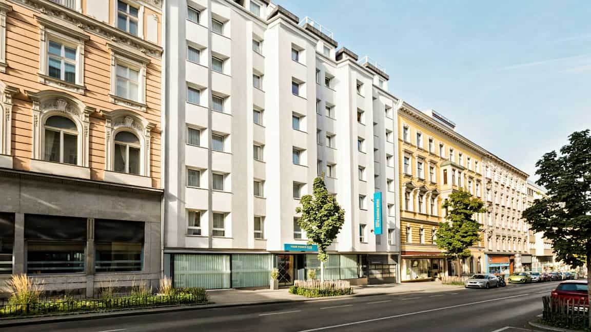 Kaupunkikatu, jossa on eri vuosikymmenten rakennuksia, mukaan lukien valkoseinäinen hotelli. (Tekoälyn luoma teksti)