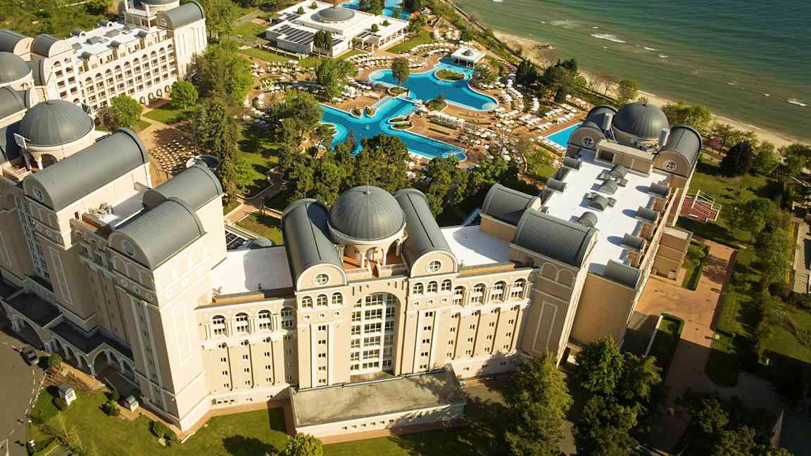 Ylhäältä kuvattu näkymä hotellikompleksista, jossa on uima-altaita ja ranta. (Tekoälyn luoma teksti)