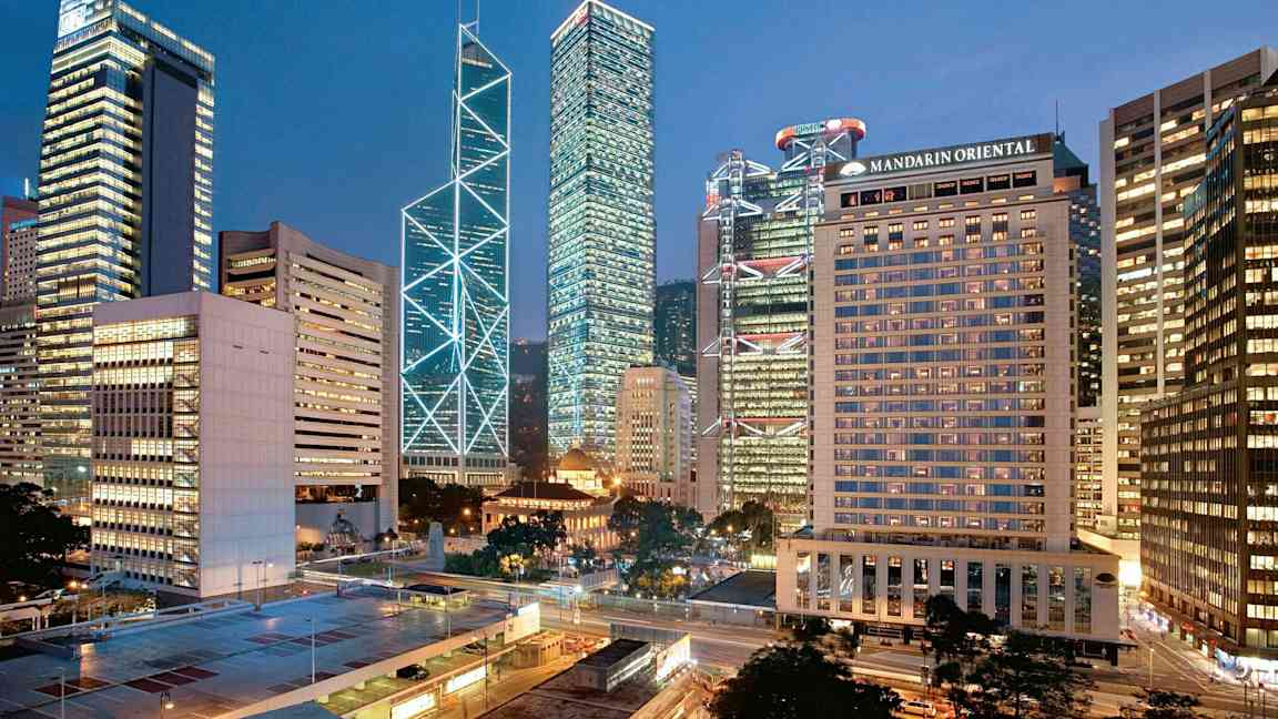 Kaupunkinäkymä, jossa korkeita rakennuksia valaistu iltavalossa. (Tekoälyn luoma teksti)