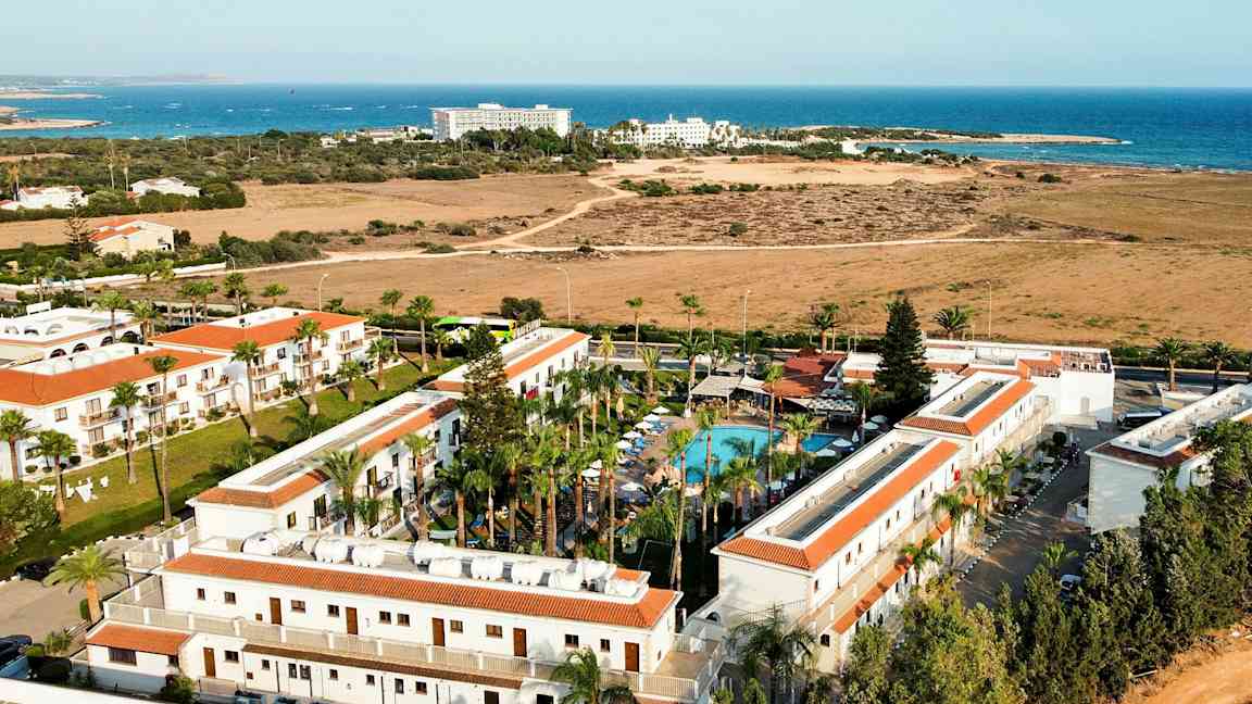 Lentokuva hotellialueesta, jossa on uima-allas ja taustalla meri. (Tekoälyn luoma teksti)