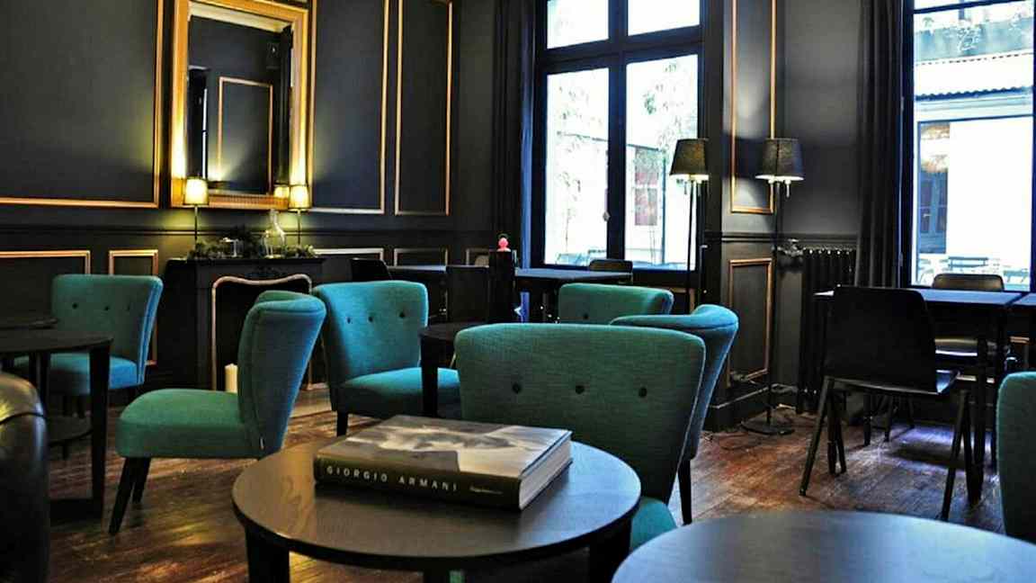 Tyylikkäästi sisustettu huone, jossa istuinryhmiä ja sinisiä nojatuoleja sekä suuret ikkunat. (Tekoälyn luoma teksti)