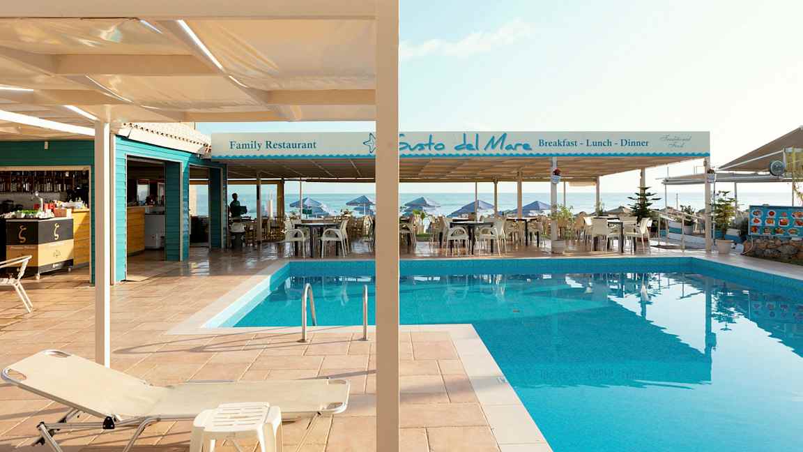 Kuva uima-altaasta terassilla, jossa on ravintoloita meren äärellä. (Tekoälyn luoma teksti)