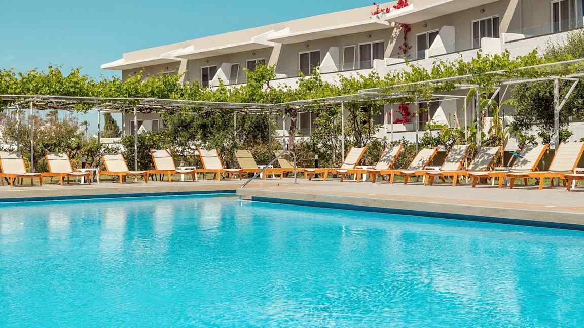 Ulkouima-allas rivin aurinkotuoleja ja hotelli taustalla. (Tekoälyn luoma teksti)