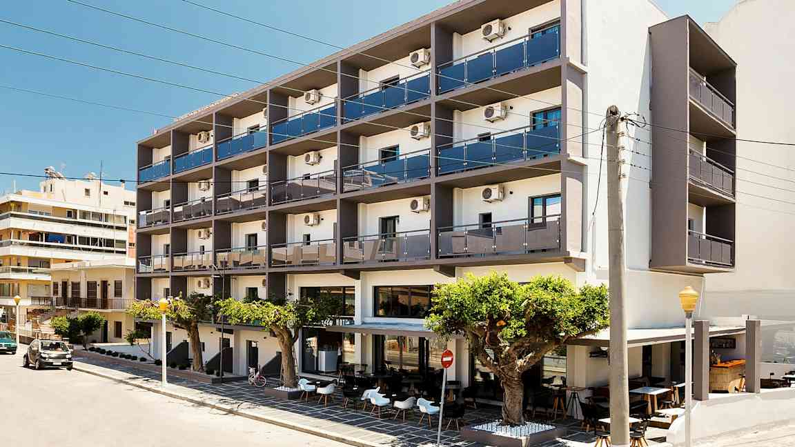 Useampikerroksinen hotelli, jossa on parvekkeita ja ulkoterassi, sijaitsee kadun varrella. (Tekoälyn luoma teksti)