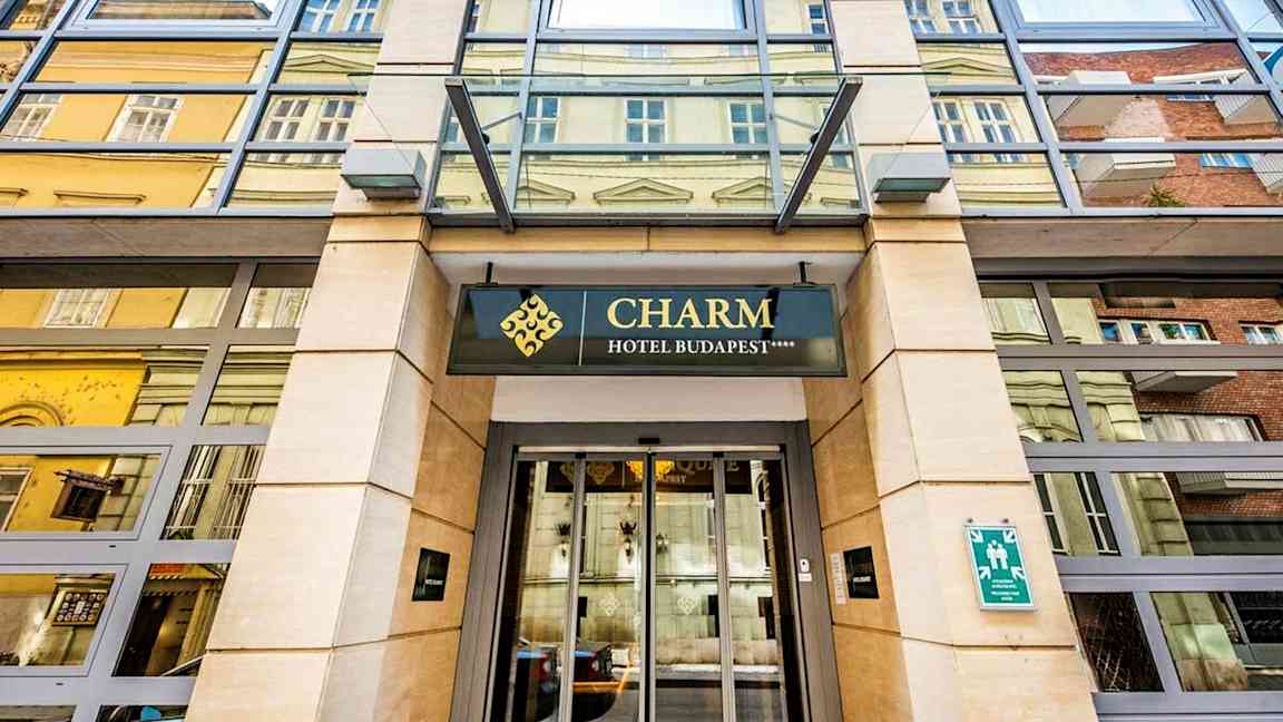 Hotellin sisäänkäynti, jossa kyltti "Charm Hotel Budapest". (Tekoälyn luoma teksti)