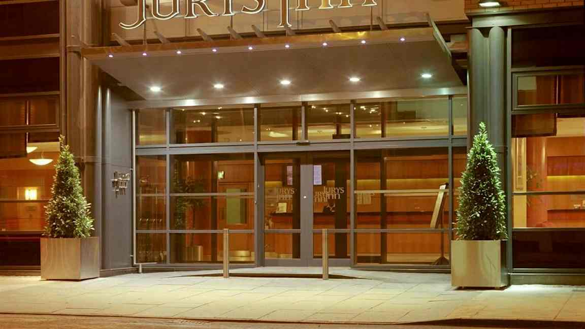 Hotellin sisäänkäynti, jossa lasiovet ja yläpuolella 'Jurys Inn' -kyltti. (Tekoälyn luoma teksti)