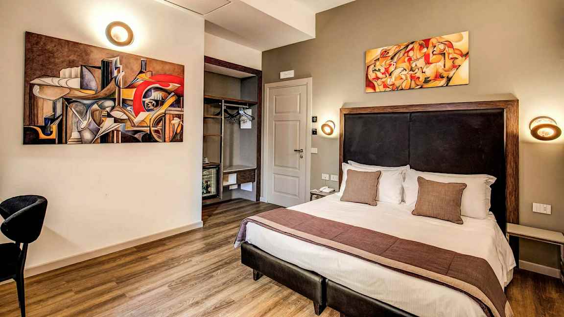 Moderni sisustus hotellihuone, jossa on parivuode ja abstrakteja taideteoksia seinillä. (Tekoälyn luoma teksti)