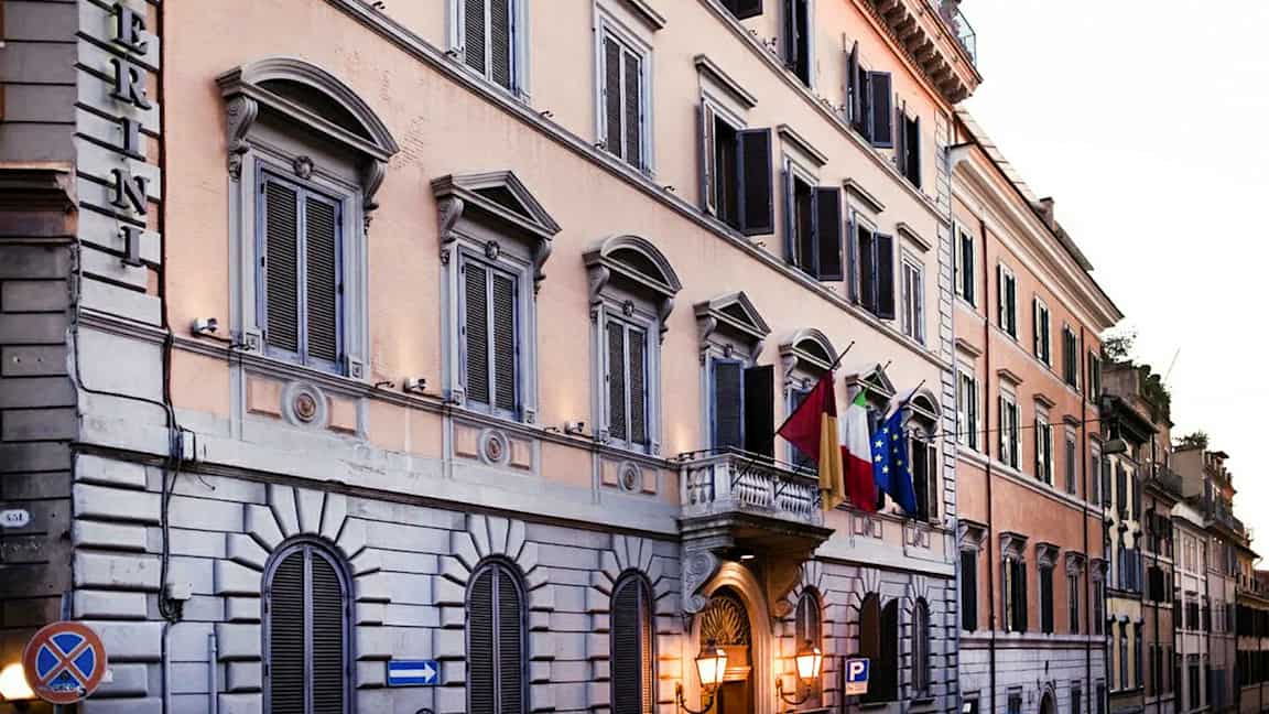 Rakennus, jossa on ikkunaluukut ja lippuja sisäänkäynnin luona. (Tekoälyn luoma teksti)