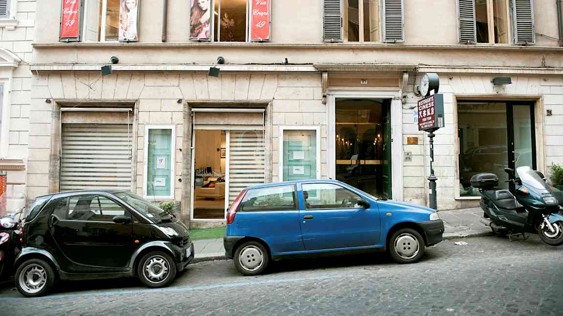 Rakennuksen julkisivu, edessä pysäköityjä autoja. (Tekoälyn luoma teksti)