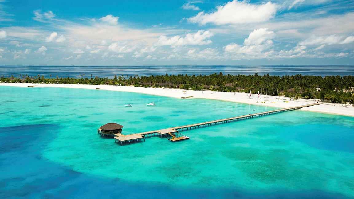 Ilmakuva trooppisesta rannasta, jossa on laituri, joka ulottuu turkoosiin veteen. (Tekoälyn luoma teksti)