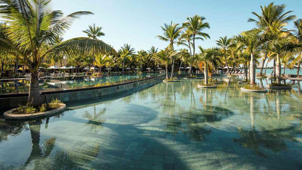 Suuri uima-allas, jota ympäröivät palmut kirkkaansinisen taivaan alla. (Tekoälyn luoma teksti)