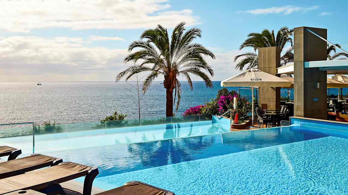 Kuvassa on infinity-allas merinäkymän edessä palmuja. (Tekoälyn luoma teksti)