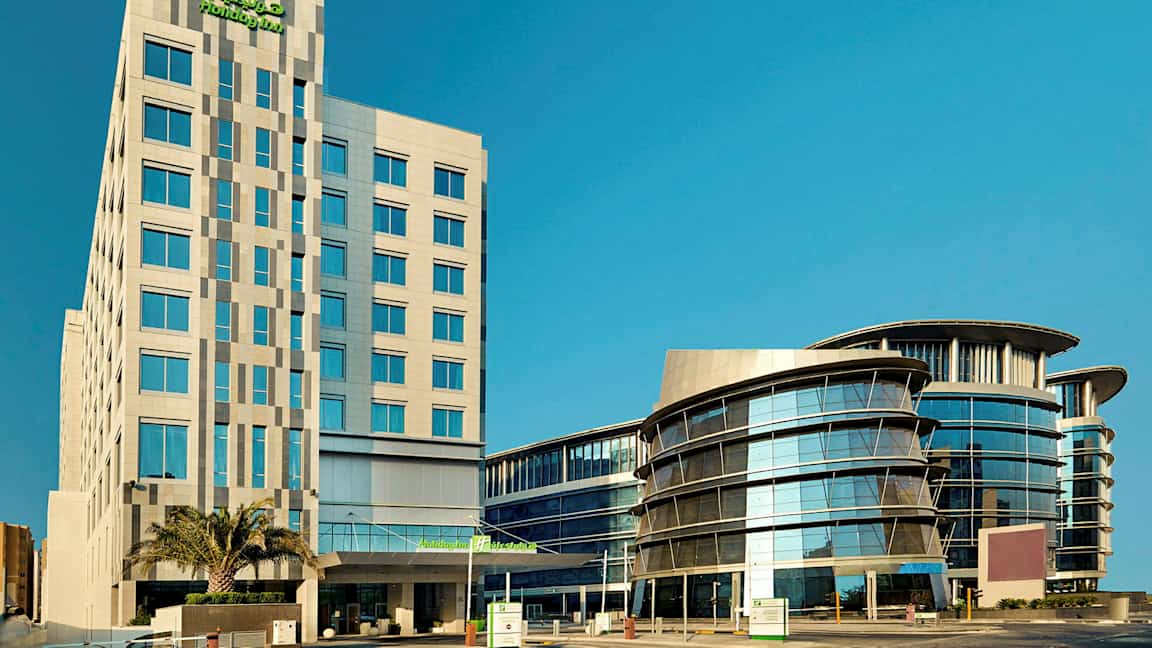 Nykyaikainen monikerroksinen rakennus jossa on lasijulkisivuja kirkkaan sinisen taivaan alla. (Tekoälyn luoma teksti)