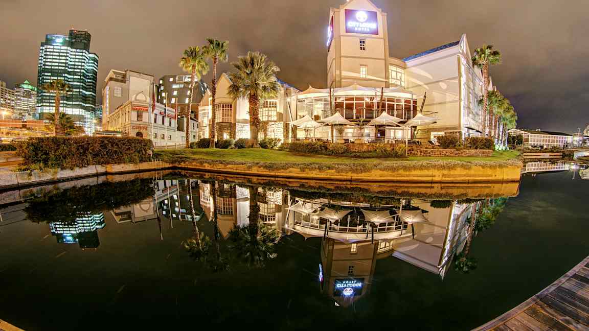 Hotelli ja rakennuksia kanavan varrella yöllä, heijastuksia vedessä. (Tekoälyn luoma teksti)