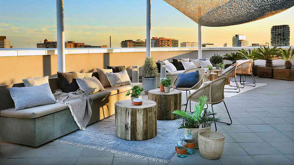 Kuvassa on kattoterassi, jossa on istuimia, pöytiä ja koreja koristeltuina kasveilla ja tyynyillä. (Tekoälyn luoma teksti)