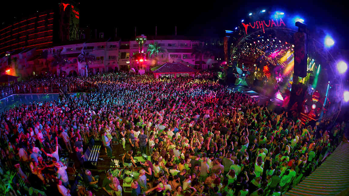 Yökerho, jossa yleisö seisoo värikkäästi valaistun lavan edessä. (Tekoälyn luoma teksti)