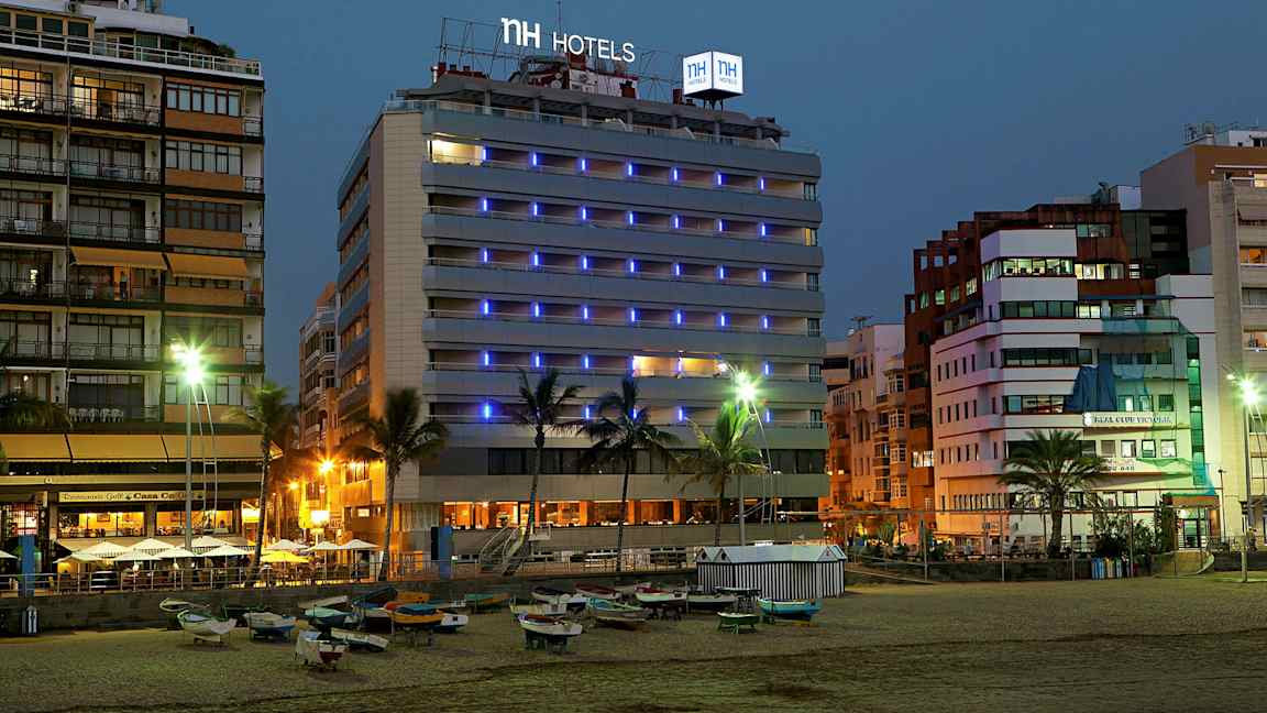 Kuva hotellista meren rannalla illalla, valokyltit ja ympäröivät rakennukset näkyvät. (Tekoälyn luoma teksti)