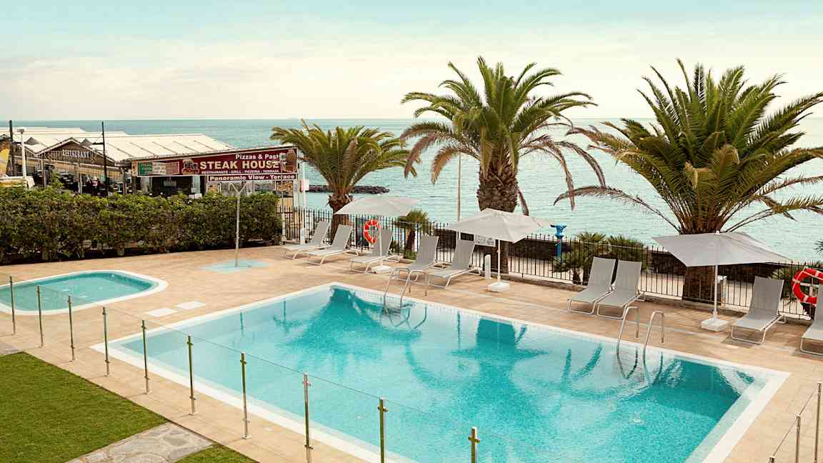 Uima-allasalue aurinkotuoleilla ja aurinkovarjoilla rannan vieressä. (Tekoälyn luoma teksti)