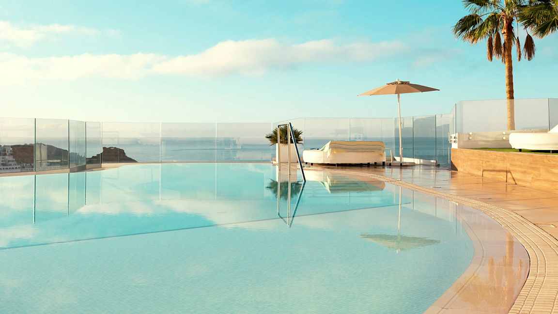 Äärettömyysallas merinäköalalla, ympäröitynä aurinkotuoleilla ja palmuilla. (Tekoälyn luoma teksti)