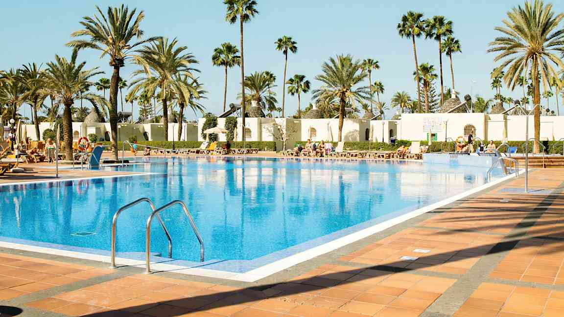 Ulkouima-allas, jota ympäröivät aurinkotuolit ja palmut. (Tekoälyn luoma teksti)