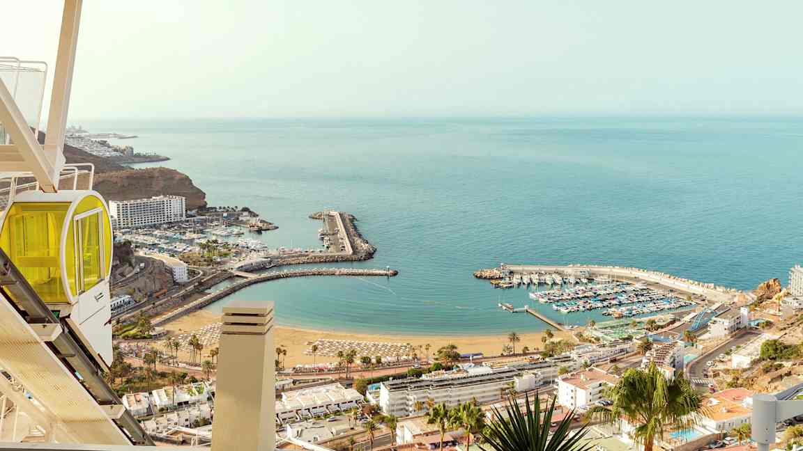 Näkymä satamaan ja rannalle meren äärellä, nähtynä korkealta, etualalla gondoli. (Tekoälyn luoma teksti)