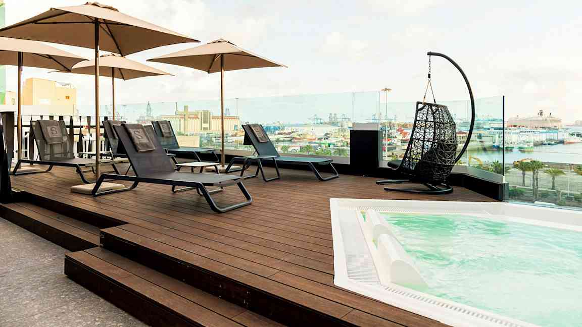 Kattoterassi aurinkotuoleilla, varjoilla ja porealtaalla, näkymä satamaan. (Tekoälyn luoma teksti)