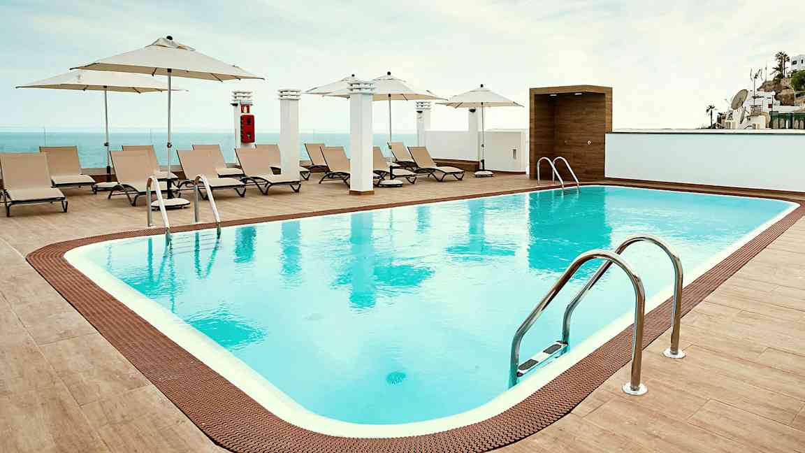 Ulkouima-allas, jonka reunalla on aurinkotuoleja ja aurinkovarjoja. (Tekoälyn luoma teksti)