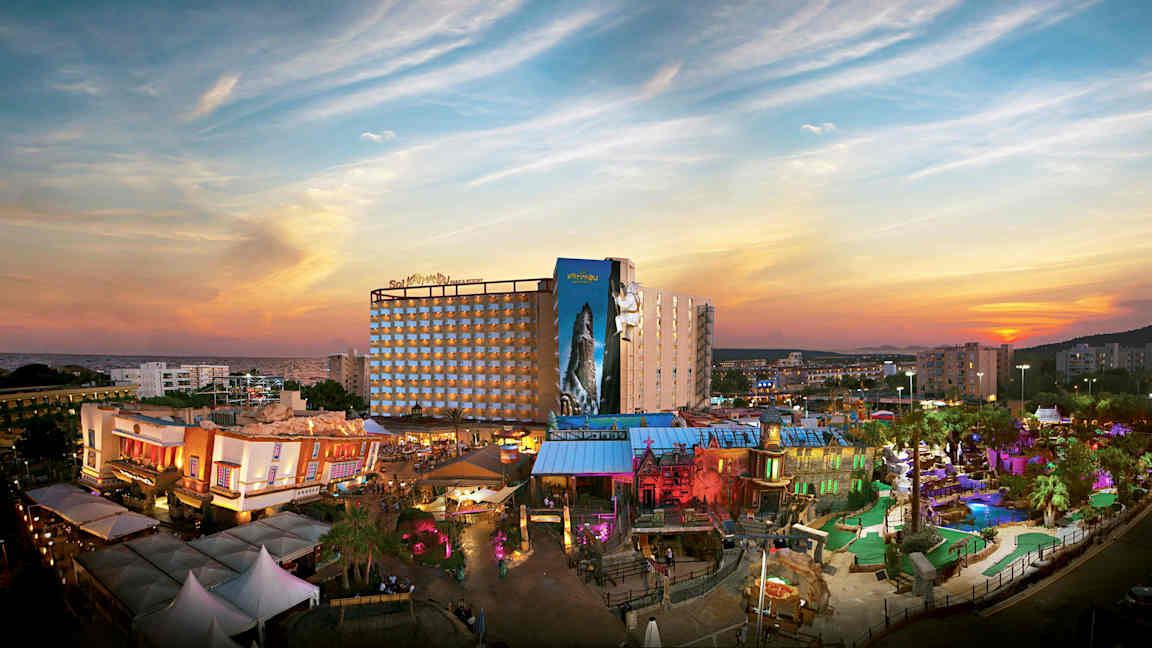 Näkymä lomahotelliin ja värikkääseen teemapuistoon auringonlaskun edessä. (Tekoälyn luoma teksti)