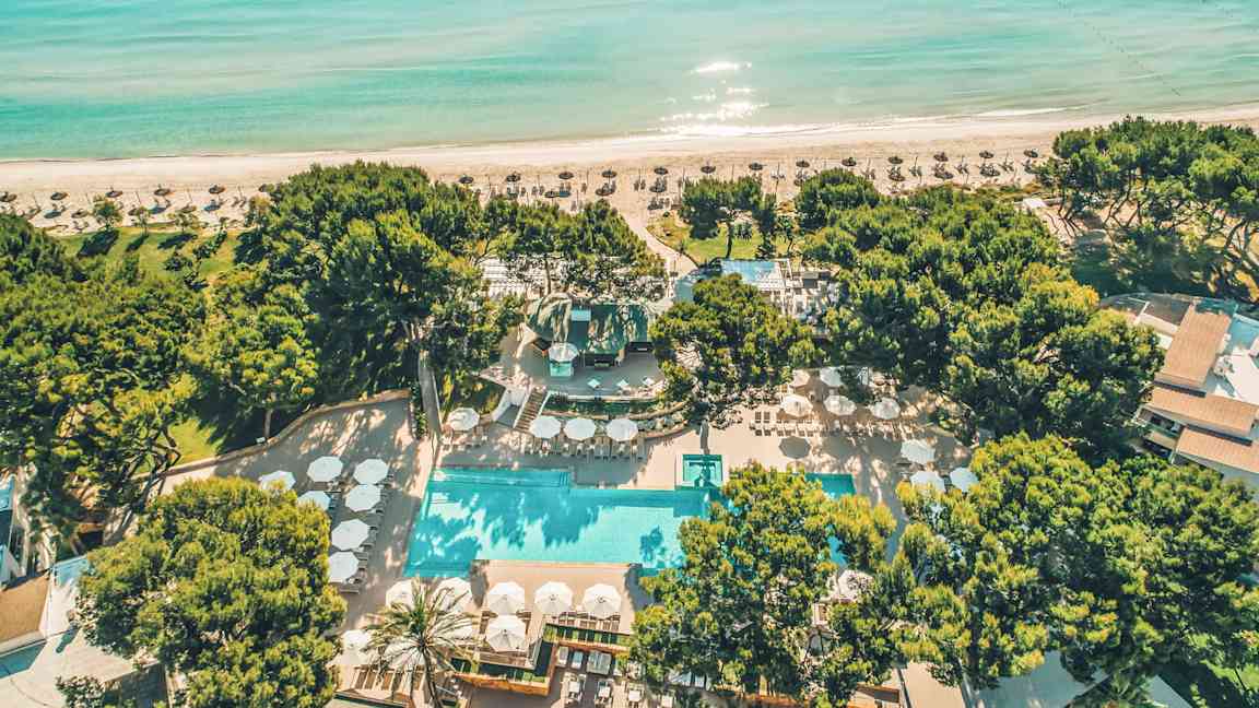 Ilmakuva lomakeskuksesta, jossa on uima-allas, ympäröitynä puilla ja taustalla oleva ranta. (Tekoälyn luoma teksti)