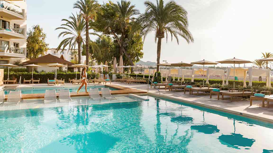 Uima-allas, jossa on aurinkotuoleja ja aurinkovarjoja hotellialueella. (Tekoälyn luoma teksti)