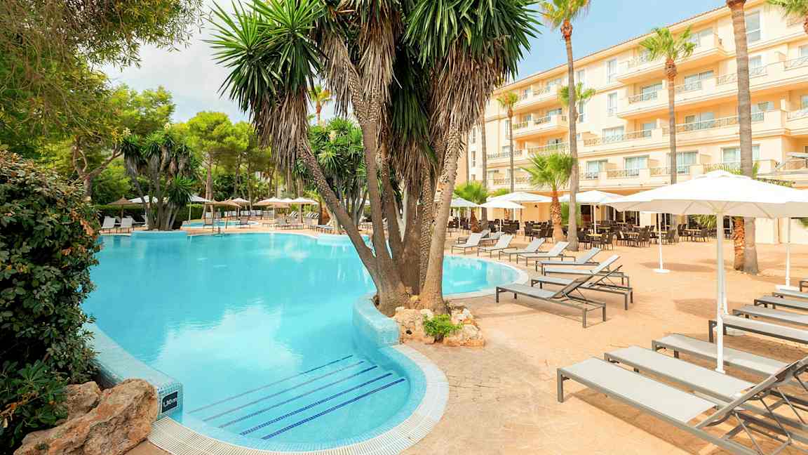 Hotellialue uima-altaalla, palmuilla ja aurinkotuoleilla. (Tekoälyn luoma teksti)