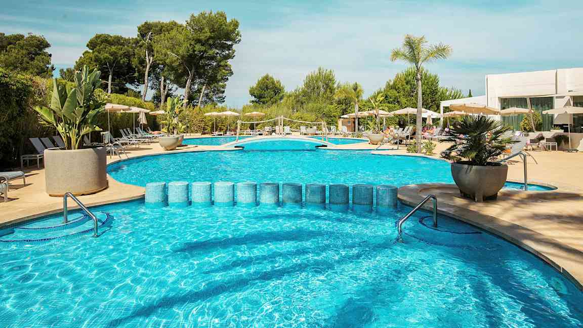 Ulkouima-allas aurinkotuoleilla ja aurinkovarjoilla sekä ympäröivää vehreyttä. (Tekoälyn luoma teksti)