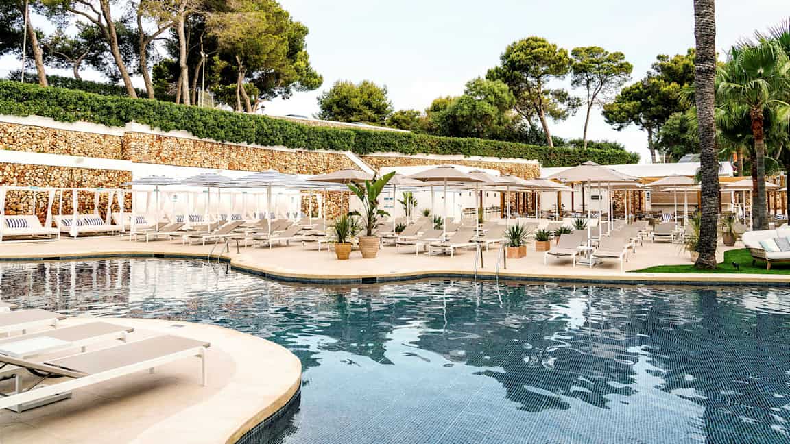 Ulkouima-allas aurinkotuoleineen ja varjoineen, ympärillä vihreitä puita ja istutuksia. (Tekoälyn luoma teksti)