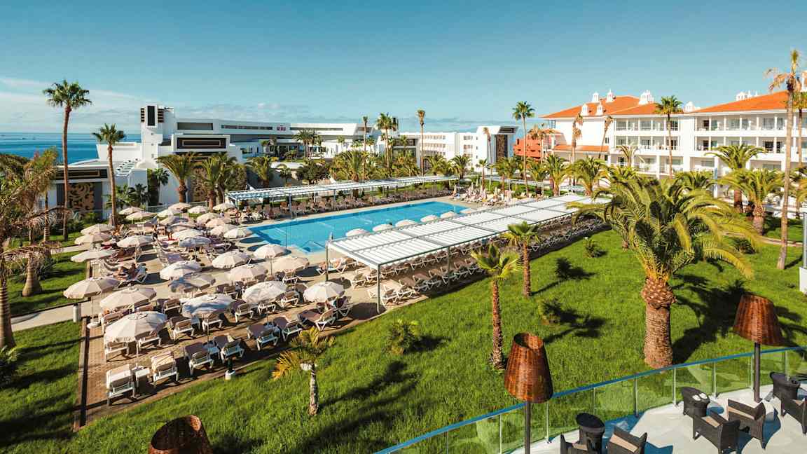 Hotellialue, jossa on uima-allasalue aurinkotuoleineen ja aurinkovarjoineen. (Tekoälyn luoma teksti)