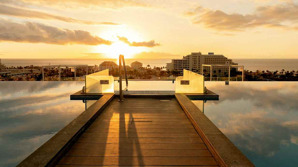 Infinity-allas puusillalla ja näkymä merelle auringonlaskun aikaan. (Tekoälyn luoma teksti)