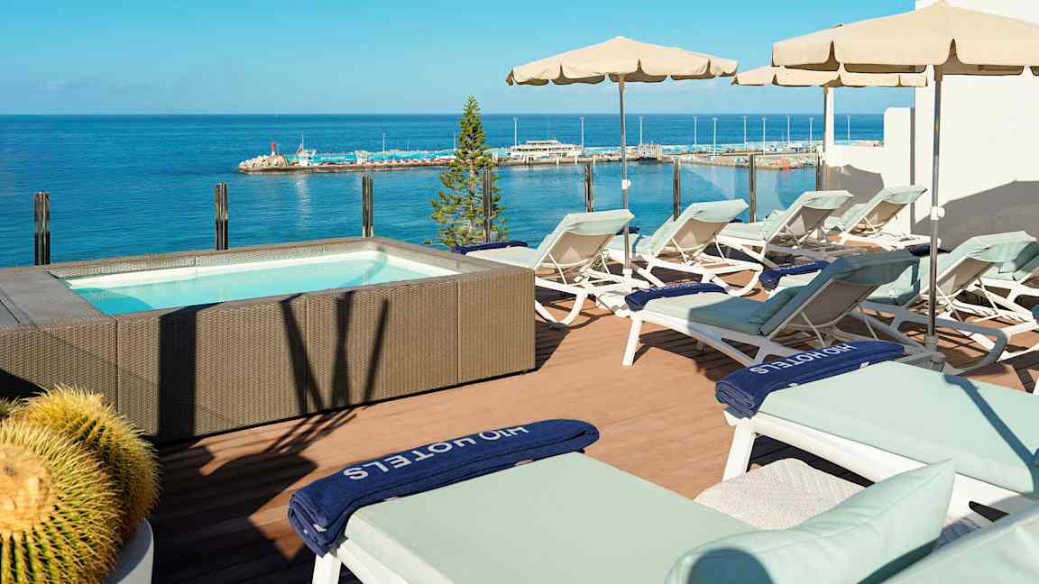 Terassi aurinkotuoleilla ja aurinkovarjoilla porealtaan vieressä, josta on merinäköala. (Tekoälyn luoma teksti)