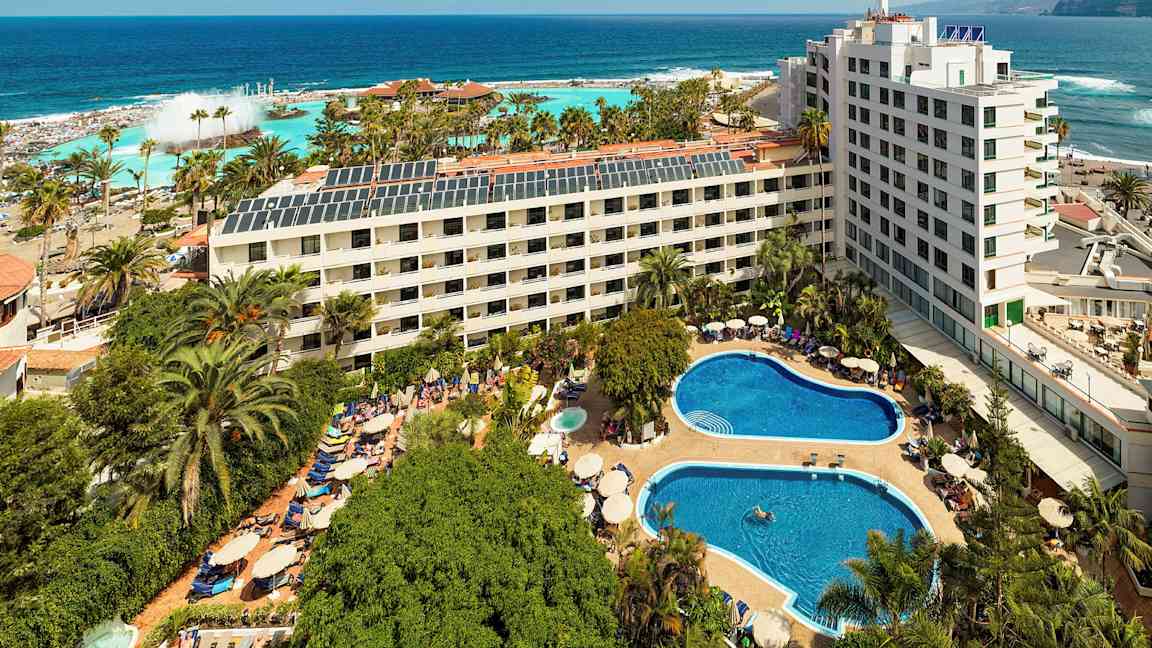 Hotellikompleksi, jossa on uima-altaita ja vehreyttä lähellä merta. (Tekoälyn luoma teksti)