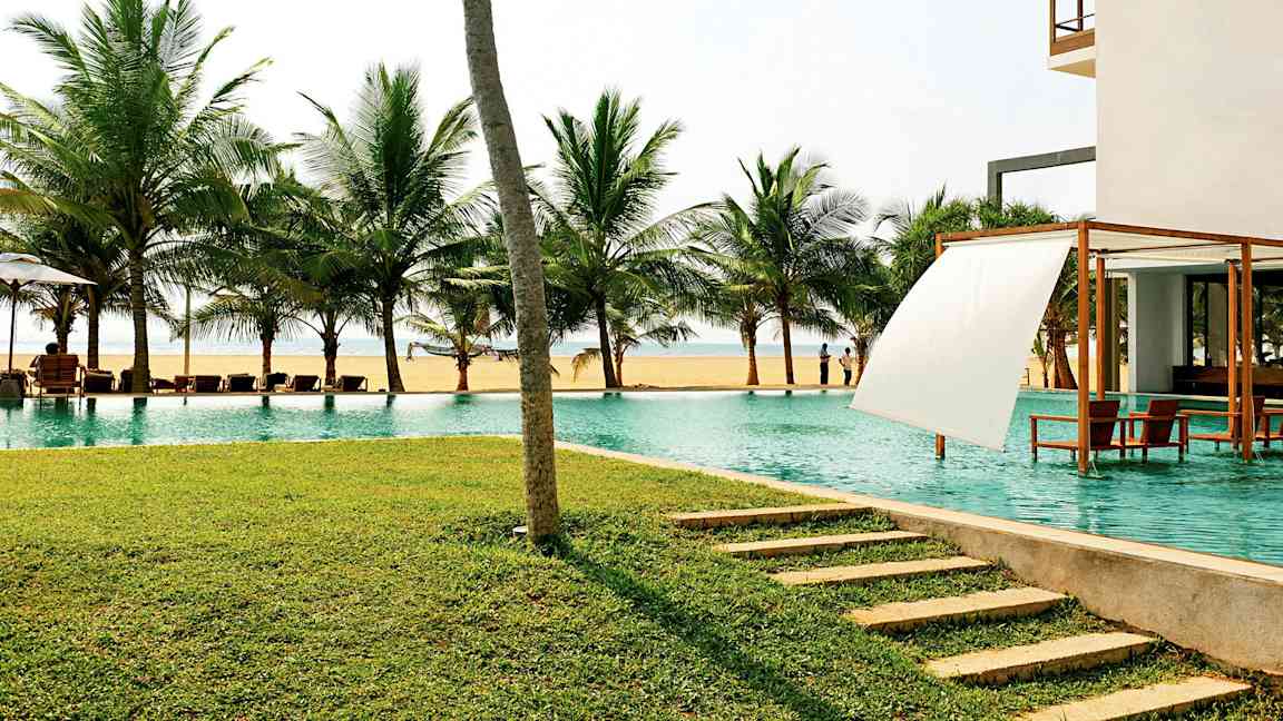 Uima-allas meren äärellä, taustalla palmuja ja etualalla nurmikko. (Tekoälyn luoma teksti)