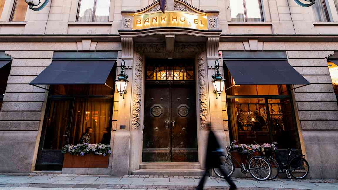 Rakennuksen julkisivu, jossa Bank Hotellin sisäänkäynti, selkeät yksityiskohdat ja valaistus. (Tekoälyn luoma teksti)