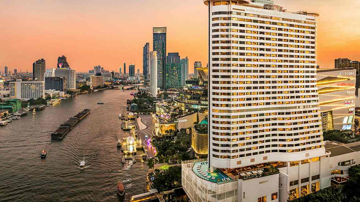 Näkymä joelle, jota ympäröivät korkeat rakennukset auringonlaskun aikaan. Etualalla näkyy suuri hotelli. (Tekoälyn luoma teksti)