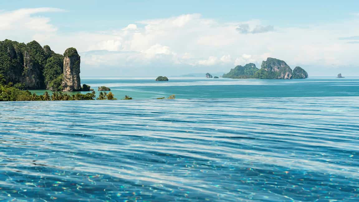 Infinity-allas etualalla, näkymä trooppiselle rannikolle ja merelle, jossa vuoristoisia saaria. (Tekoälyn luoma teksti)